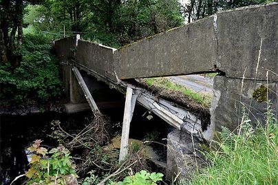 A partially collapsed bridge spans a small creek.