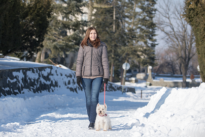 woman walking dog on snowy street