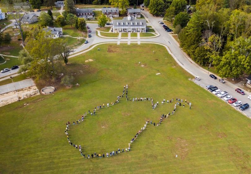 Aerial photo of the field in front of the Jackson's Mill Dining Hall with people standing in the outline of West Virginia