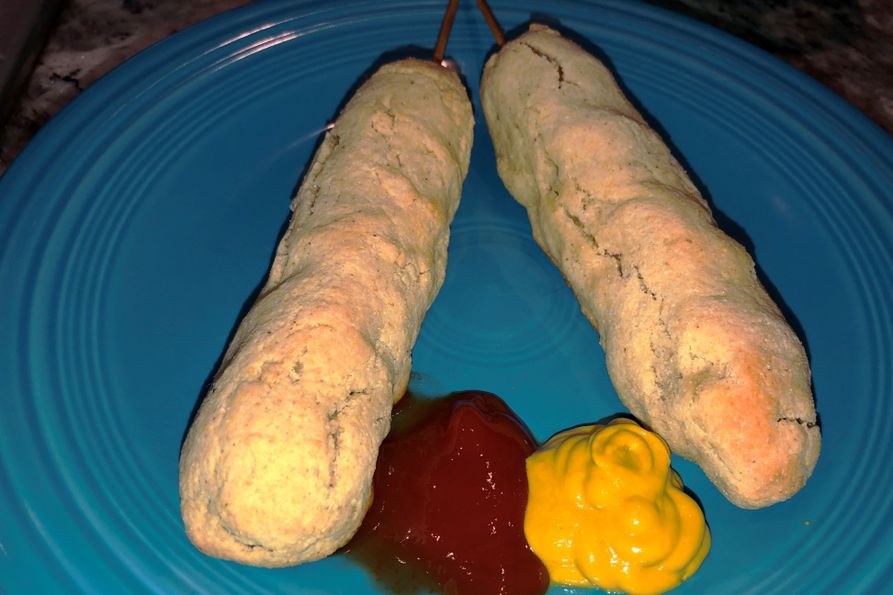 Plated baked corn dogs with ketchup and mustard.