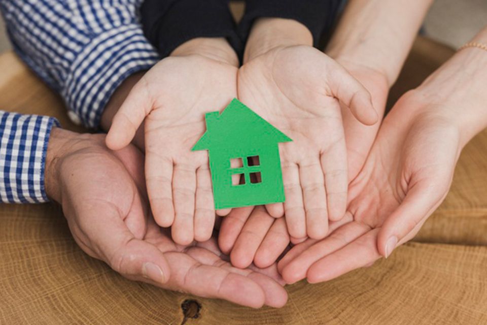 hands of family holding cutout of a house