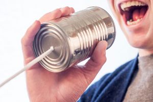 Person talking into a can with string attached