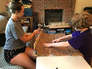 Two girls working on a plastic bag mat on a loom