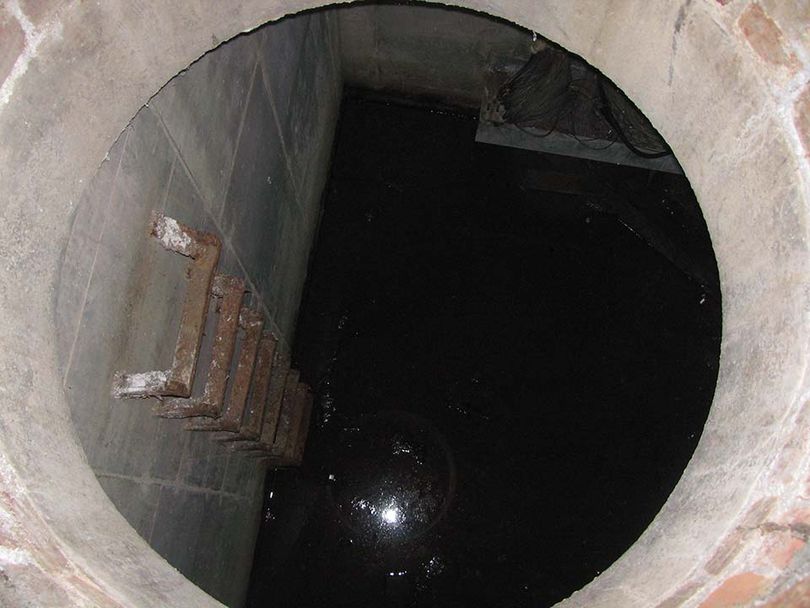 View looking down into a manhole showing ladder and water inside.