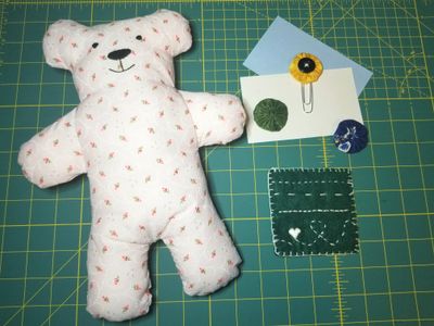 Stuffed Animal, felt mug rug, fabric yo-yos, paperclip, and index cards