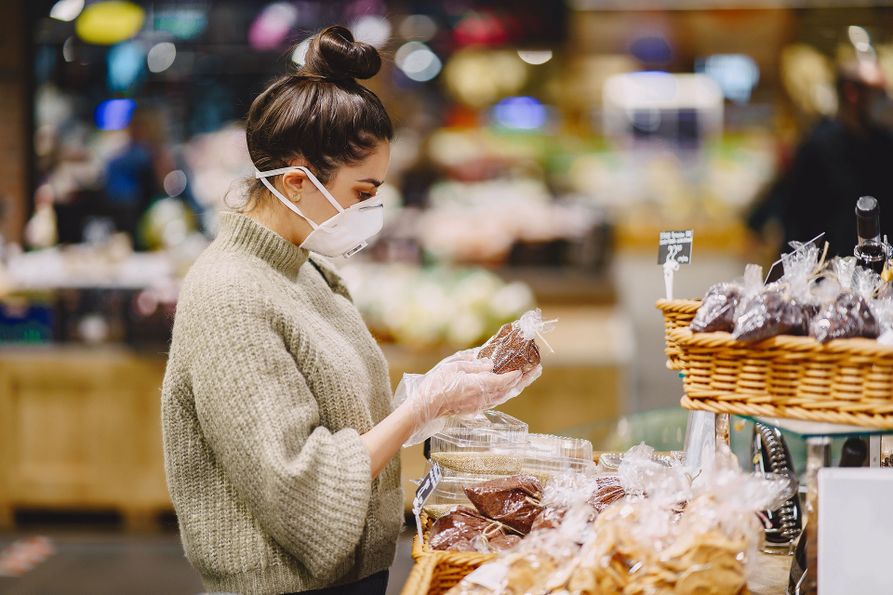 A woman shops at a market wearing a respirator and gloves.