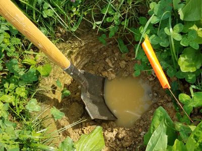 Hole filled with water illustrating poor drainage in soil.