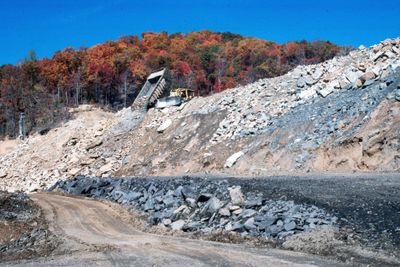 A dump truck unloads a load of fill from a mine site.
