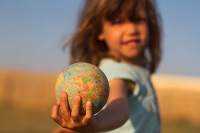 A child holds a toy globe in her hands.