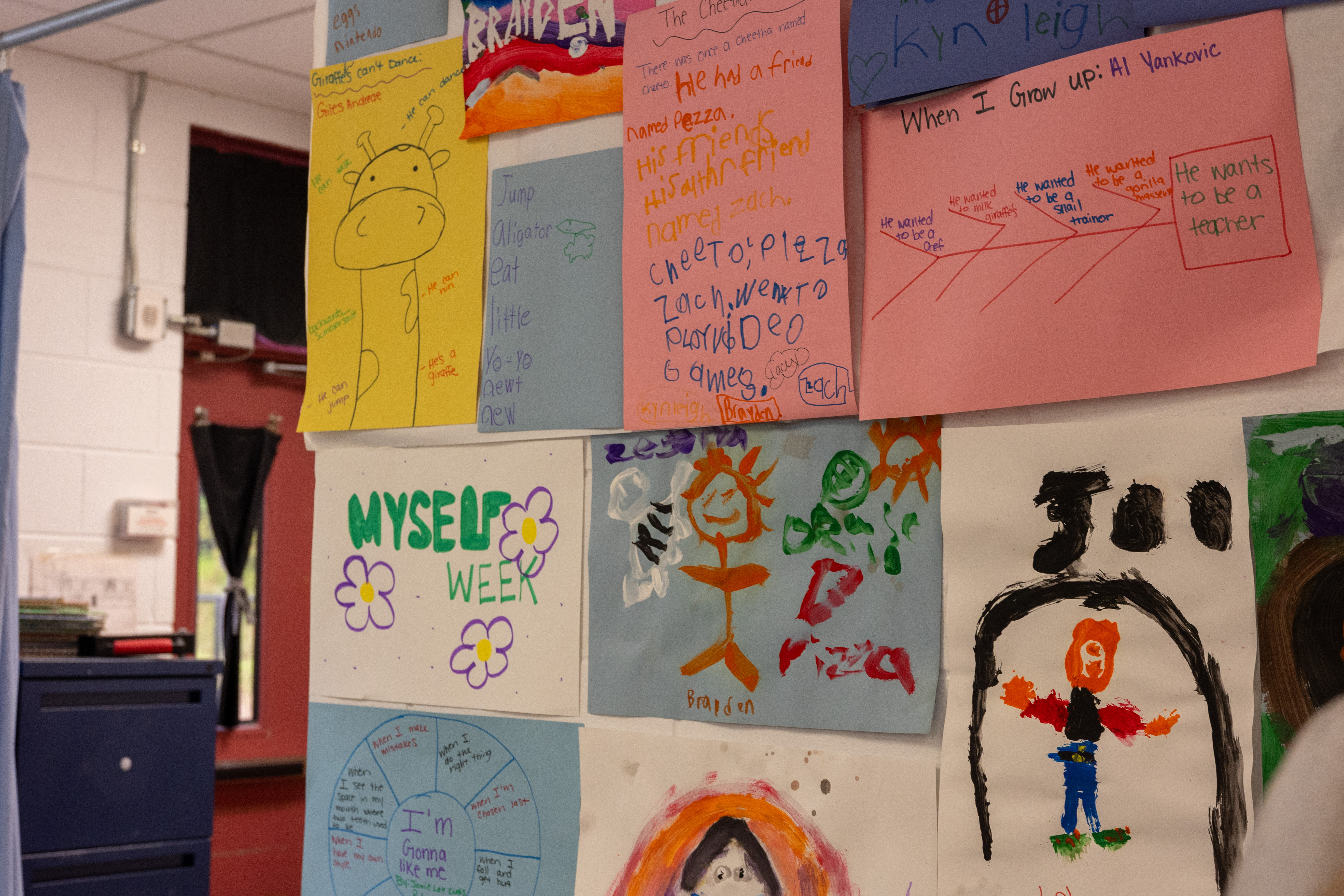 Many drawings done by young children around a sign that reads "Myself Week" at an Energy Express camp.