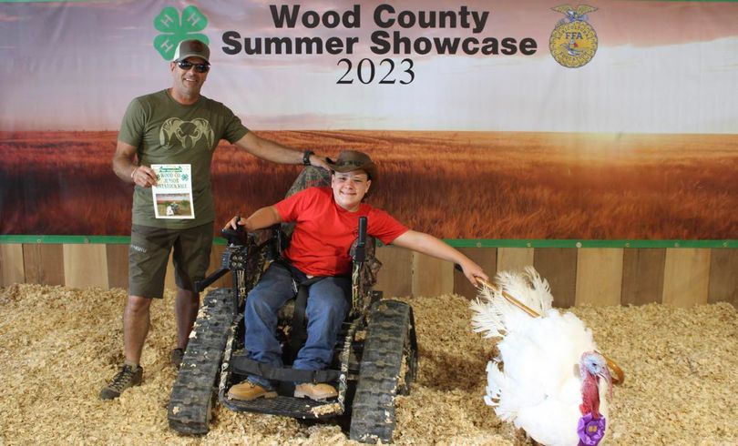 A boy in a wheel chair with his champion turkey