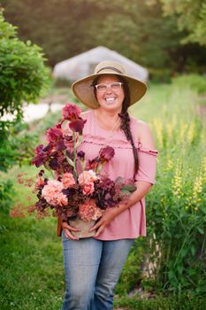 Jennie Love standing in a field of flowers, holding a fresh picked bouquet.