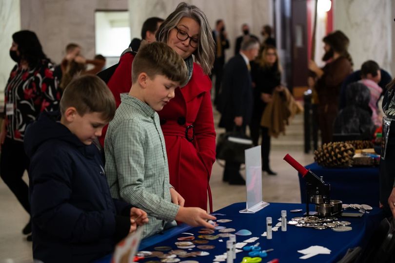 Two male students stand at WVU 4-H button making table at WVU Day at the Legislature at the State Capitol. 