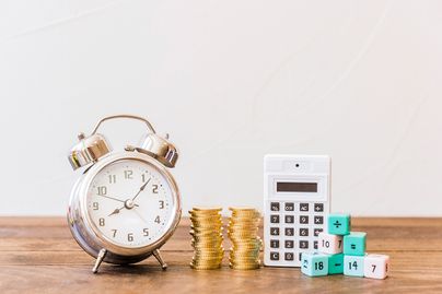 alarm clock and money and calculator on wooden table