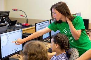 Older 4-H'er helps younger 4-H'ers with their coding projects