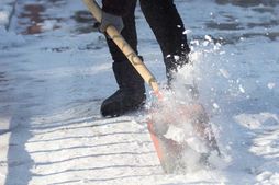 person pushing snow shovel to clear snow