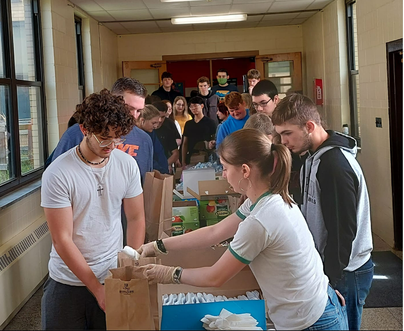 a group of youth around a table assembling brown bags with food and supplies