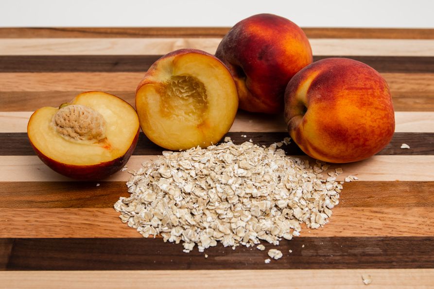 Peaches and oats on a wooden cutting board. 