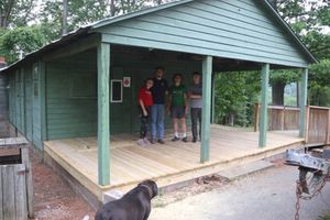 four youth standing on the porhc of a cabin