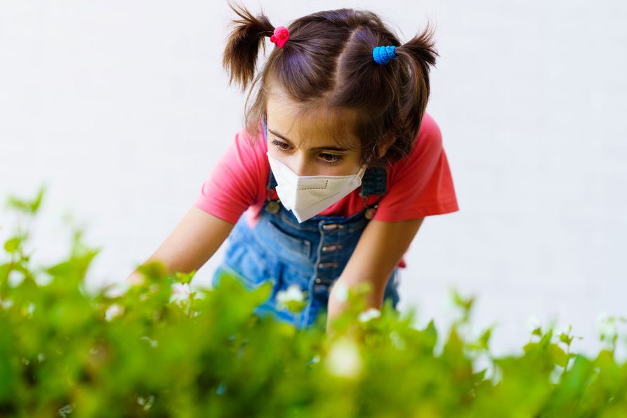 A girl wears a protective mask while picking fruit.