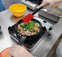 Family Nutrition Program Teen Cuisine participant stirs a colorful mixture of vegetables in a fry pan