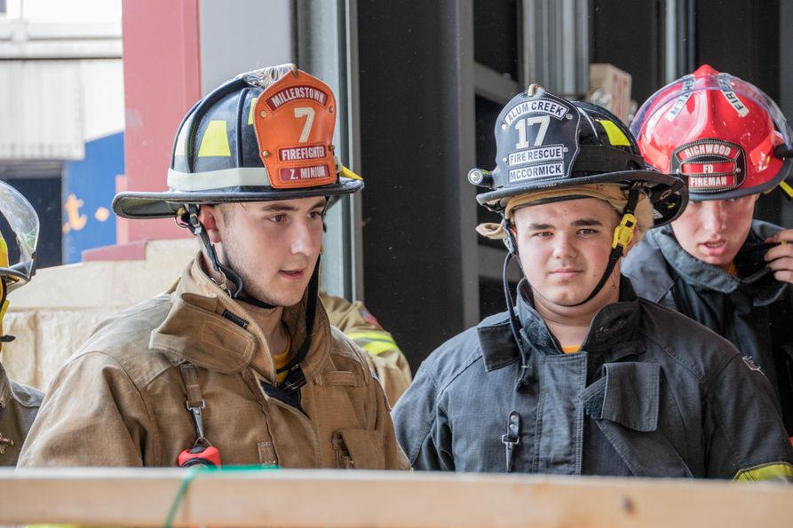 Two male junior firefighters talk during instructional drill. 