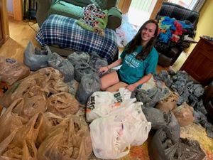 Girl sitting on floor surrounded by donations of plastic shopping bags