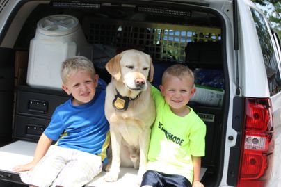 Two boys with a dog in back of vehicle