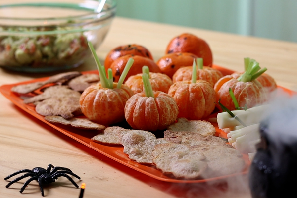tray with spooky snacks and clementine pumpkins with celery stems