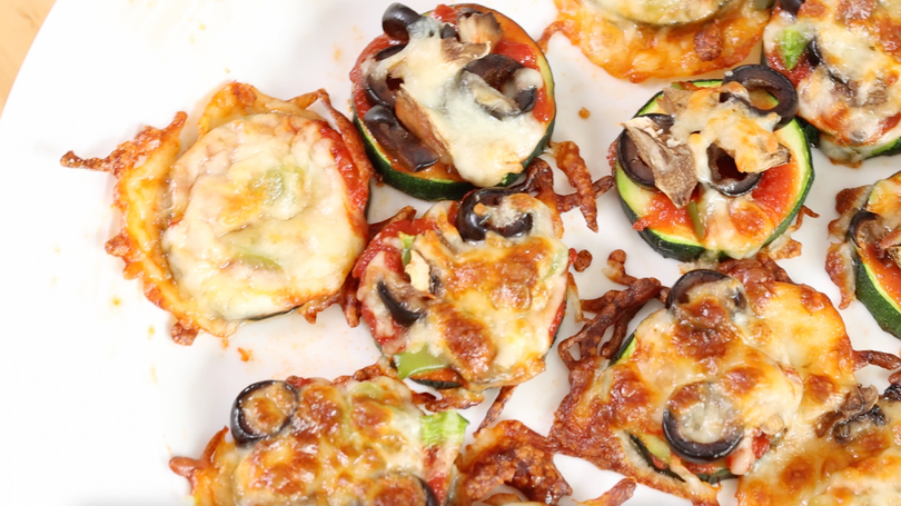 baked bite size zucchini pizzas on a sheet pan lined with parchment paper