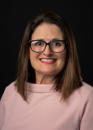 A headshot of Jennifer Williams who is wearing a pink shirt sweater and eyeglasses.