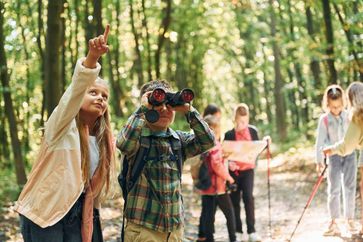 Kids explore rural tourism as tourists in the forest at summer camp, surrounded by tall green trees