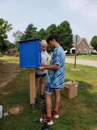 two teens installing a little library box in a yard