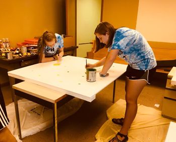 two teen girls begin painting the pattern of the "quilt"