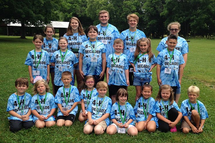 group of kindergarten children in blue 4-H t shirts pose for photo with teen counselors