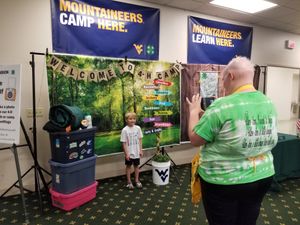 Adult taking a picture of a boy in a 4-H camp backdrop