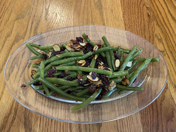 bowl of green beans, cranberries and nuts on a wooden table