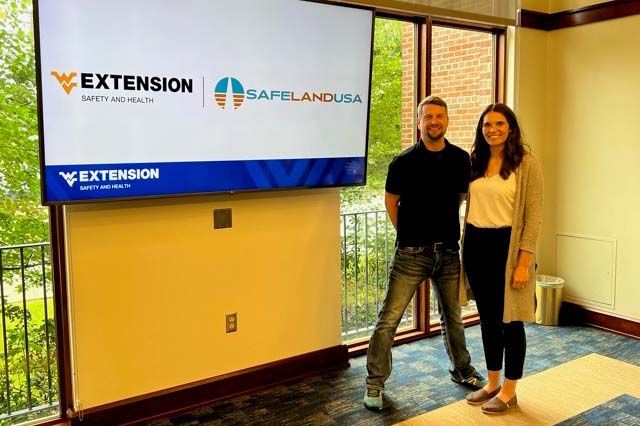 Tiffany Rice, WVU Extension safety and specialist and assistant professor, and Chris Warnick, WVU Extension safety and health adjunct instructor, standing beside presentation screen with WVU Extension Safety and Health | SafeLandUSA logo.