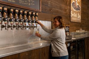 a woman pouring hard cider from a tap