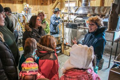 Group of youth and adult visitors gather around tour guide during an agritourism experience at Family Roots Farm.
