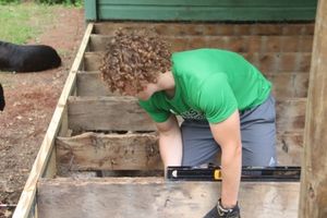 Youth replacing the floorboards of a porch