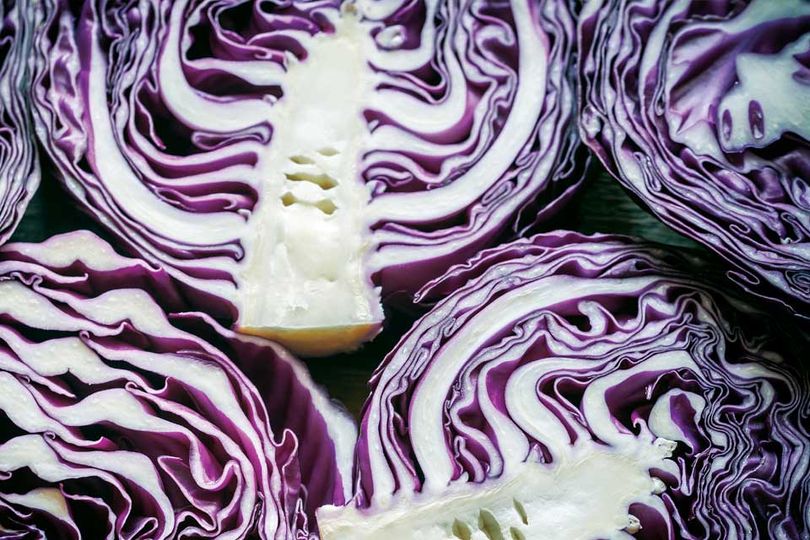 Purple cabbage cut in half show white stems.