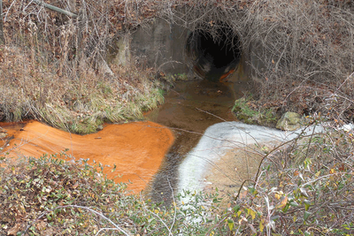 A culvert with acid mine drainage exiting to the left.