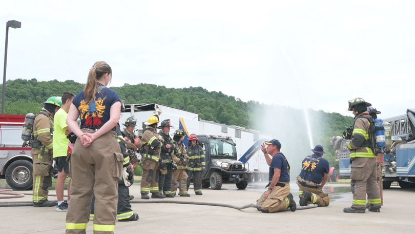 Campers learning at Junior Firefighter Camp while putting out an airplane fire.