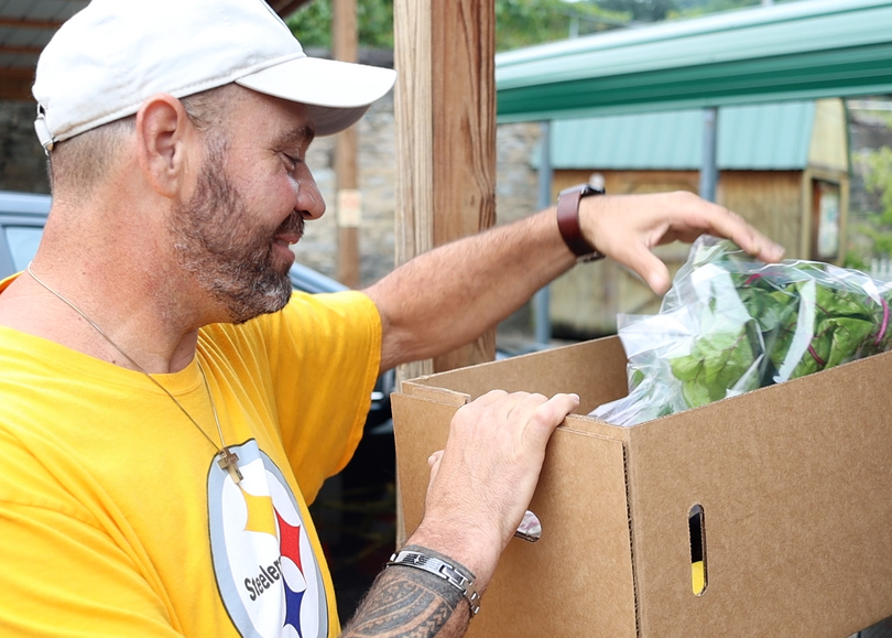 FARMacy participant Chad Eanes looks through a box of produce. Eanes is featured in a documentary about the food access program.