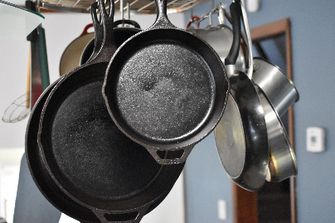 skillets and pans hanging from a rack
