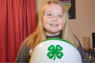 Youth holding a beachball with the 4-H clover on it