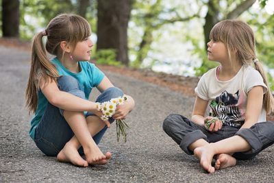 Two girls talking to each other and sitting on ground