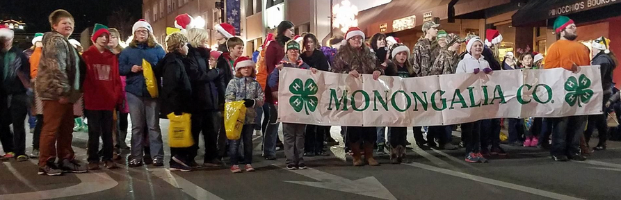 4-H members line up and prepare to walk in the parade holding a 4-H banner. 