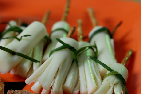 pretzel sticks, chives and string cheese assembled to make witches' brooms